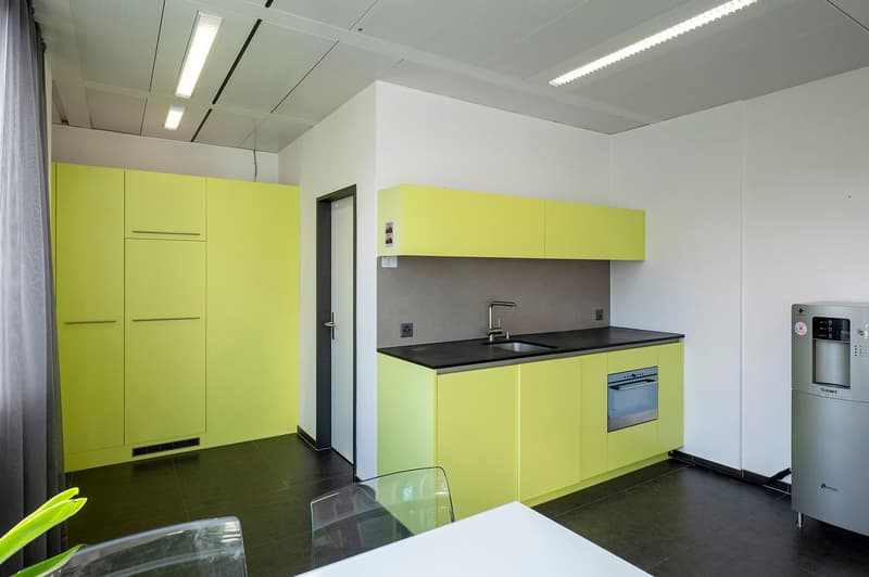a modern and compact kitchen with a small sink, oven, countertop, and bright green cabinets.
