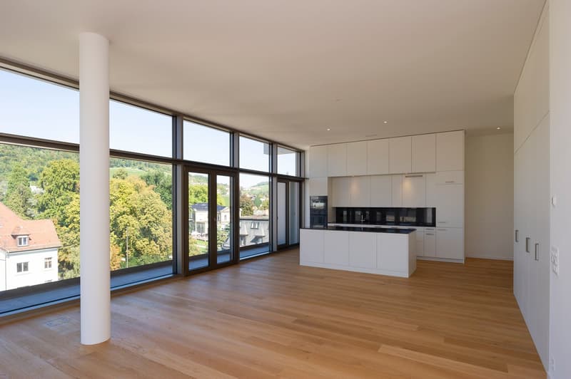 modern kitchen with a white countertop and a central island, large windows, wooden floor, balcony with view of the countryside