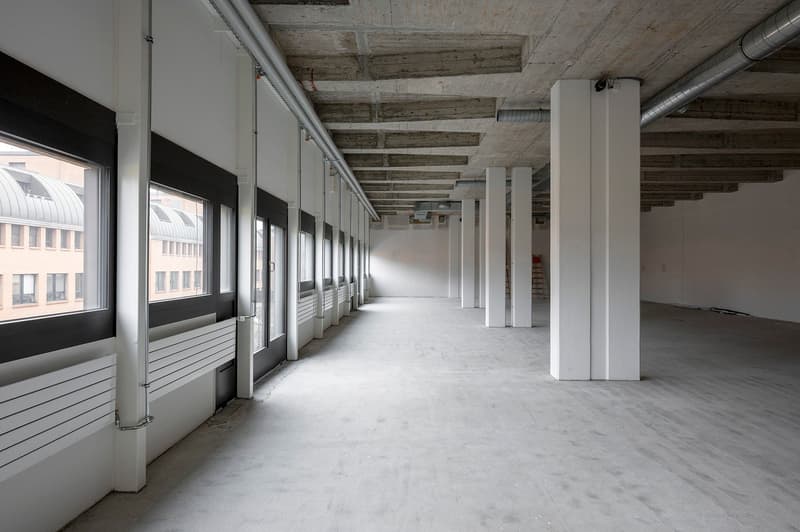 Empty corridor with concrete floors, white walls, large windows, white pillars