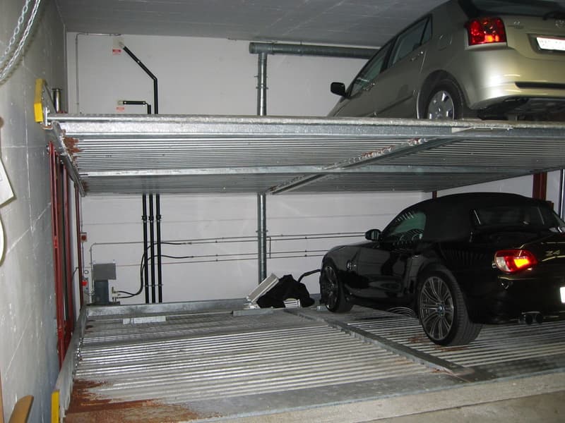 Two-level car garage with a vehicle parked on the lower level and storage space on the upper level.