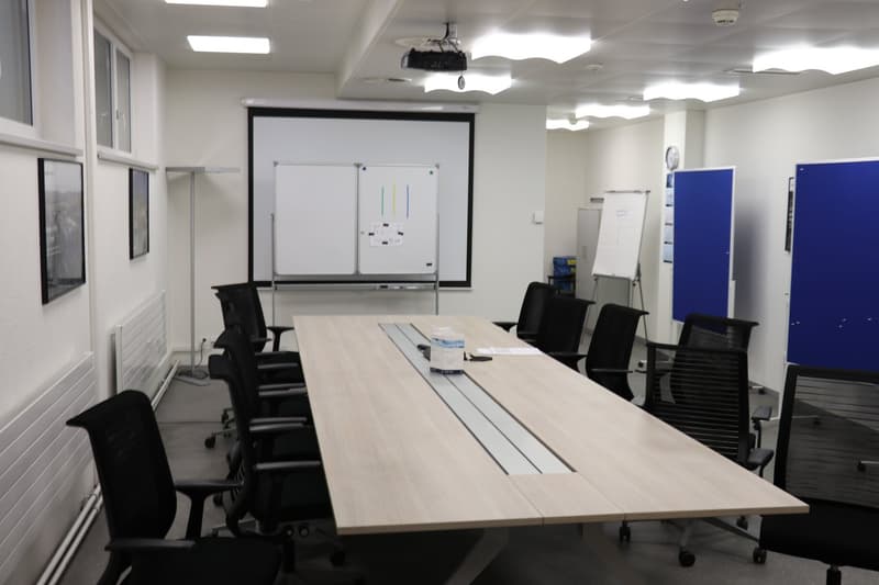 conference room with a long table, chairs, whiteboards, projector
