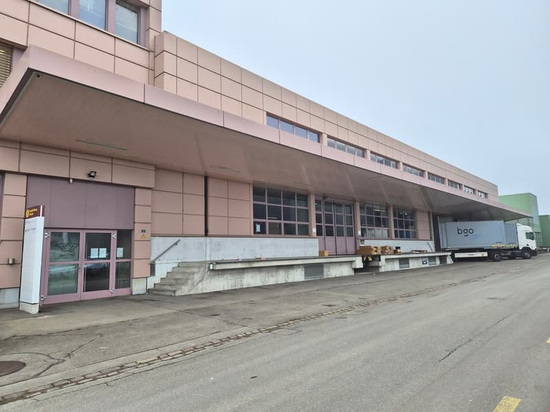 Industrial building, multiple windows, entrance, loading dock, steps, truck parking