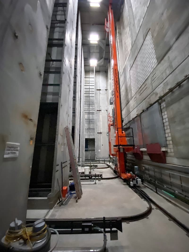 an industrial building construction with metal beams, a large crane, concrete floor, and various materials