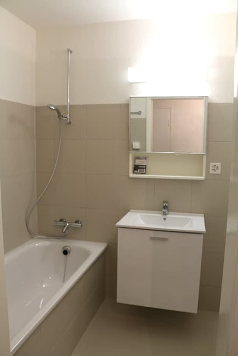 white bathtub, mirror, bathroom cabinet, faucet
