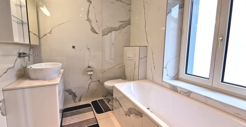 modern bathroom, white marble tiles, double sink vanity, separate toilet, bathtub, built-in toilet paper holder, double window