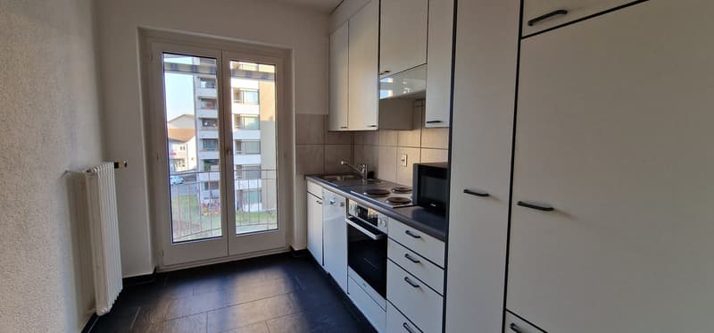kitchen with white cabinetry and modern appliances, black tiled flooring, double doors leading to a balcony