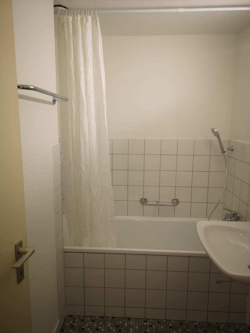 Tiled bathroom with a bathtub, shower curtain, and a sink