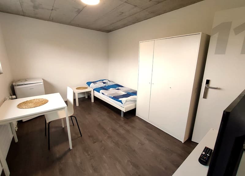 small bedroom with bed, white desk, white wardrobe, white chair, white refrigerator