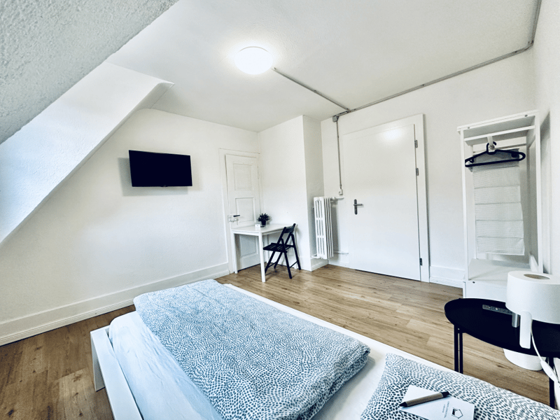 bedroom with bed, desk, chair, TV, radiator, door, wardrobe, lamp, telephone