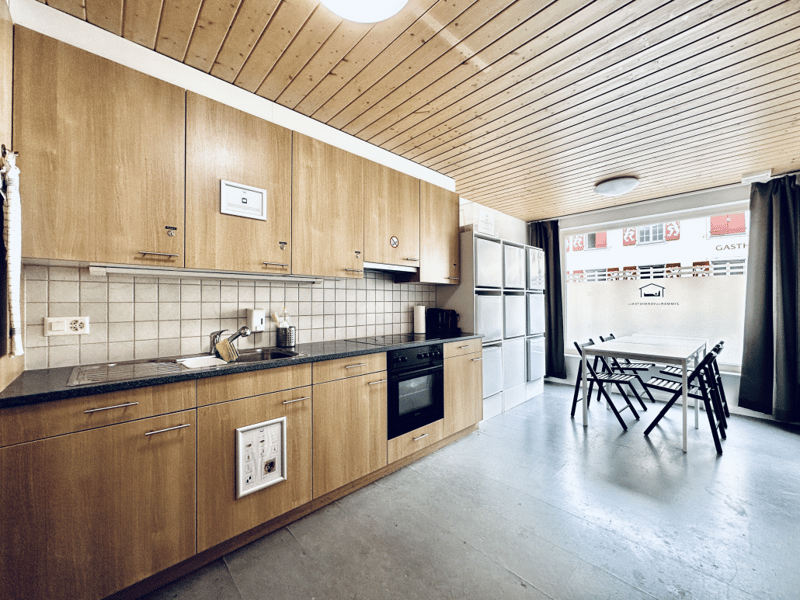 wooden cabinets, tiled backsplash, dishwasher, washing machine, black countertops, oven, sink, faucet, tile flooring