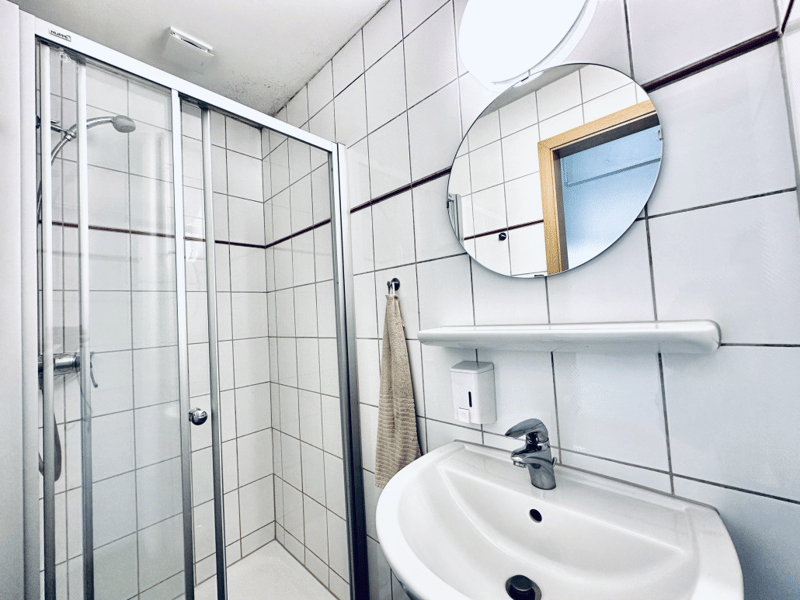 Bathroom, shower area, sink, mirror, soap dispenser, towel rack