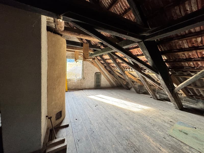 Old wooden attic room with wooden floor, exposed wooden beams, windows with yellow frames