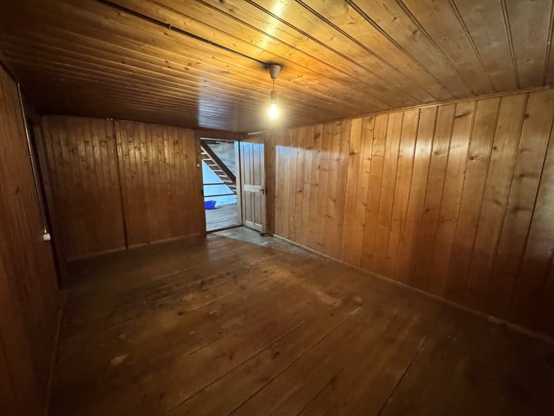bare room with wooden floor, wooden paneling on walls, single light fixture in the ceiling
