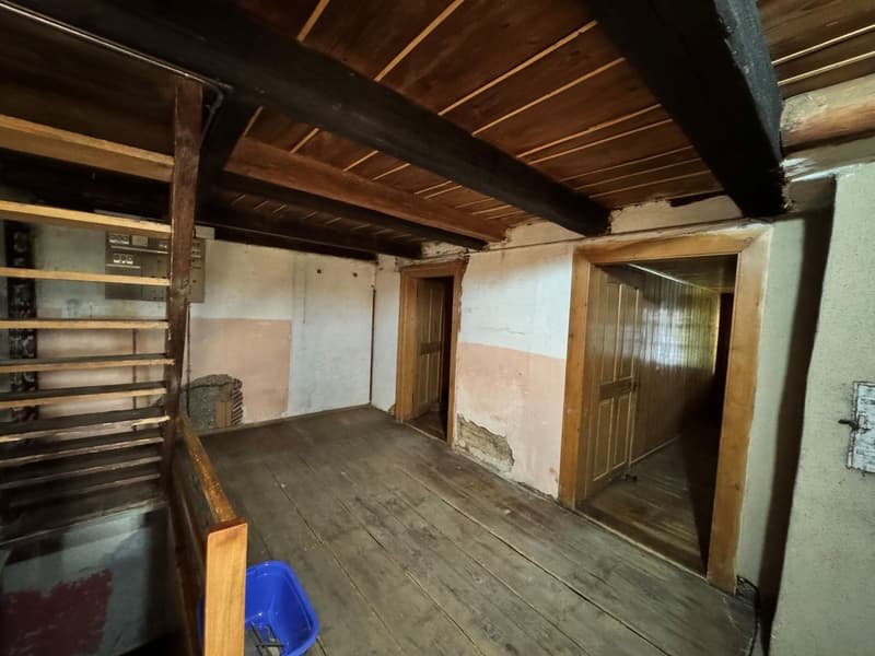 a room with a wooden staircase and floor, old wooden beams, wooden doors, and wooden walls