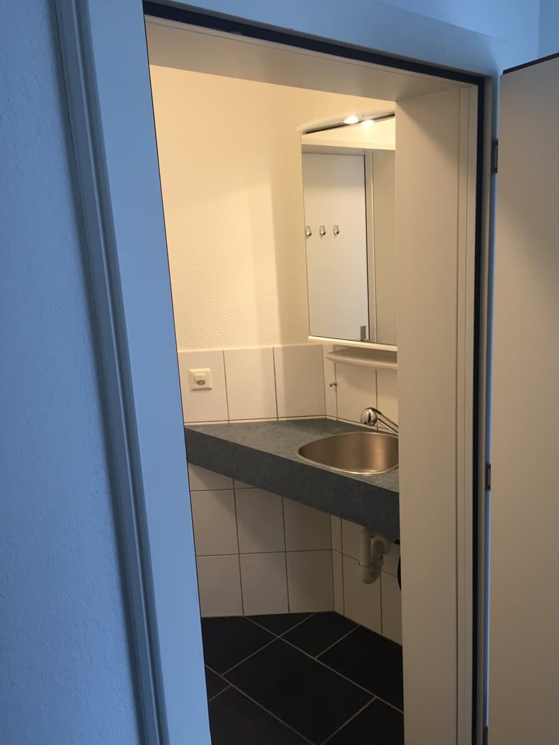empty room with bathroom sink and mirror, grey countertop, white tiles on the wall