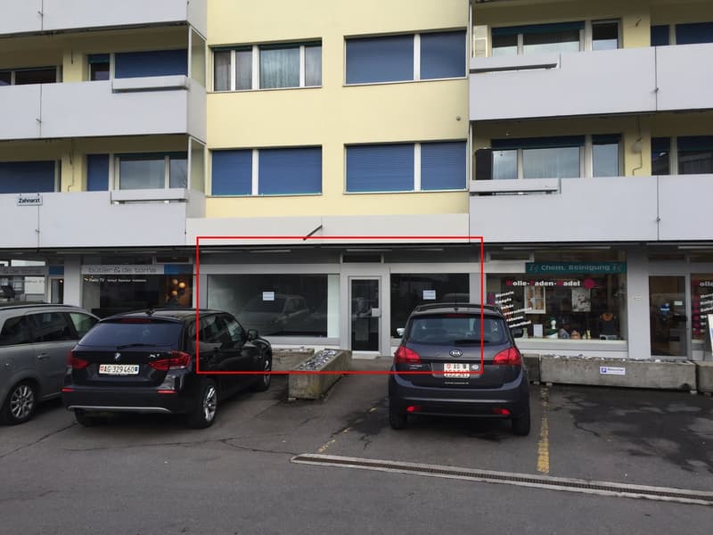 Apartment building with commercial space at the ground floor, cars parked in front of it