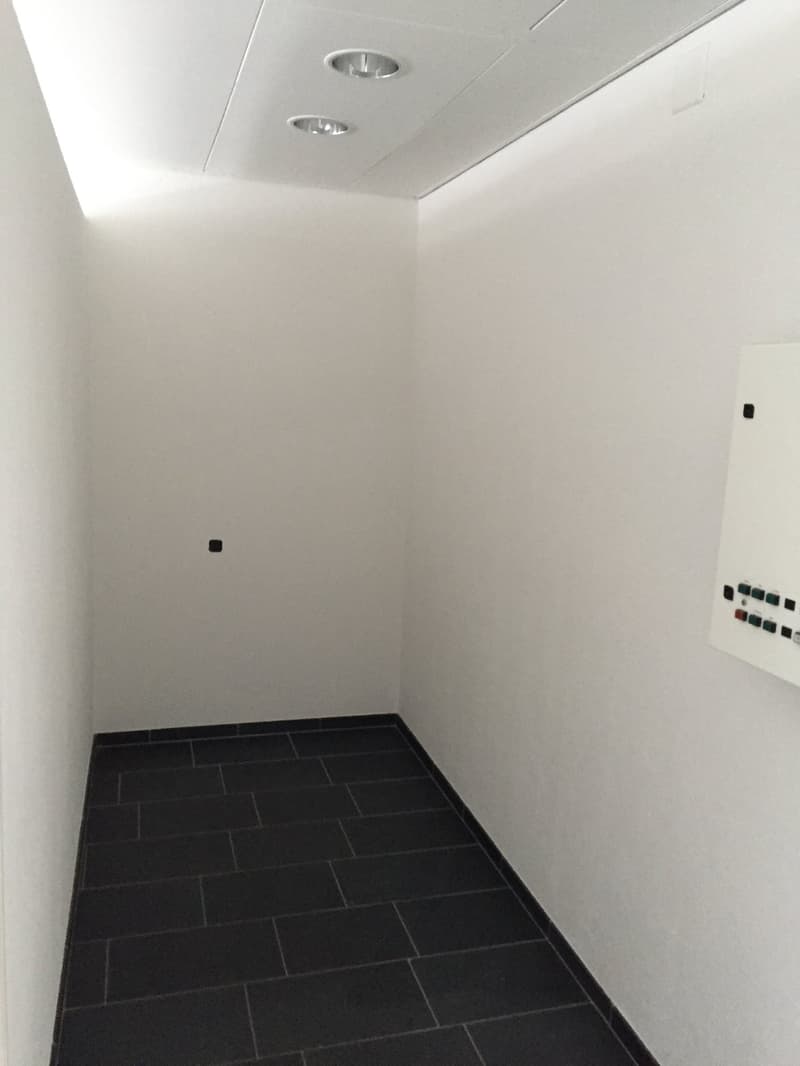 Empty room, tiled floor, white walls, ceiling with recessed lighting