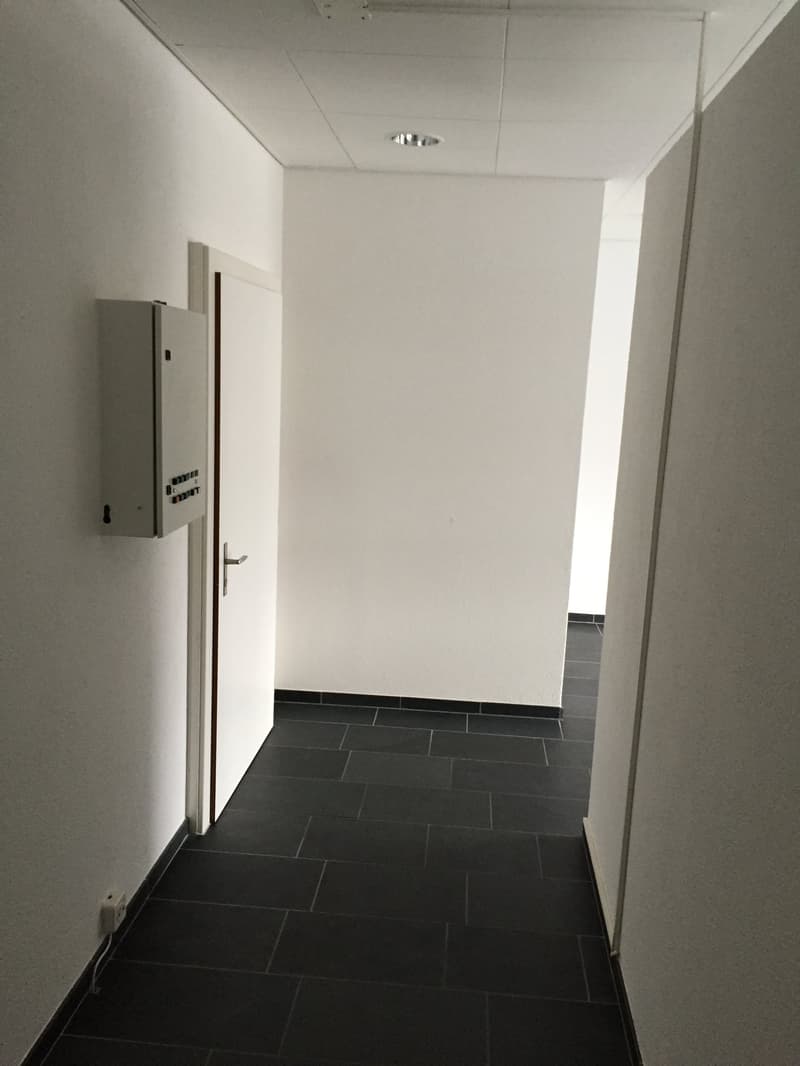 white walls, black tile floor, metal door, socket on wall