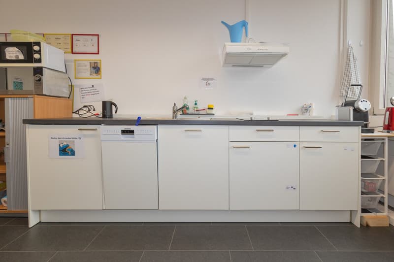 White cabinets, black countertops, built-in dishwasher, built-in washing machine, microwave, coffee machine, and shelves