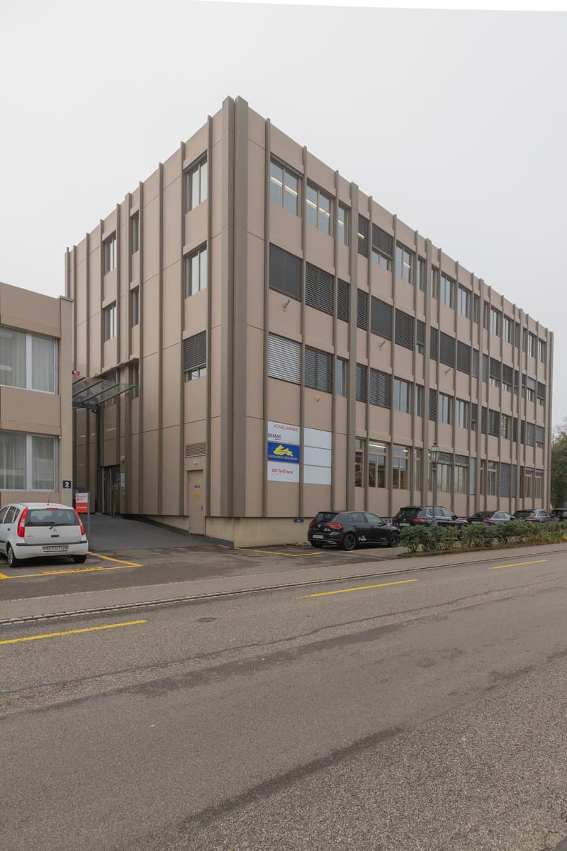 brown office building, multiple windows, signage, parking lot