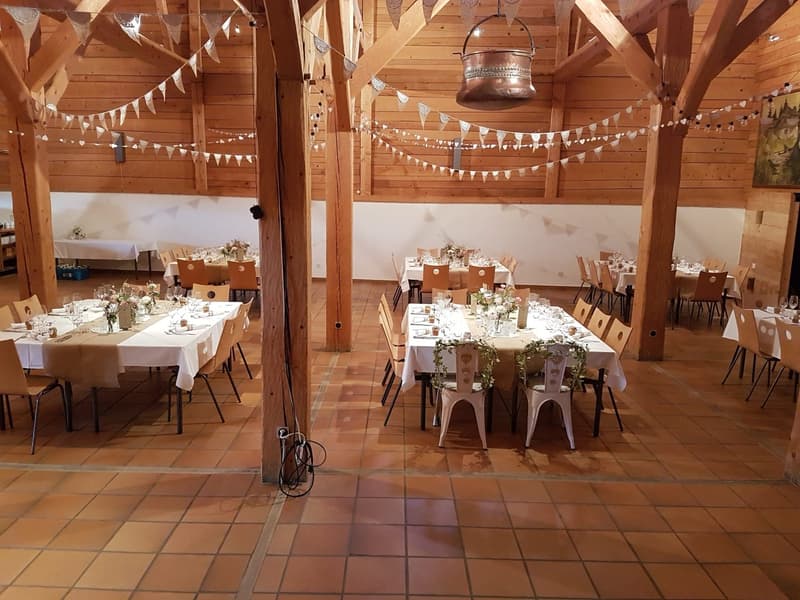 wooden ceiling, wood-paneled walls, large tables set up for dining, hanging decorations