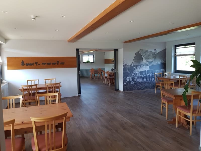 large dining area with wooden tables and chairs, wooden beams on ceiling, picture on wall