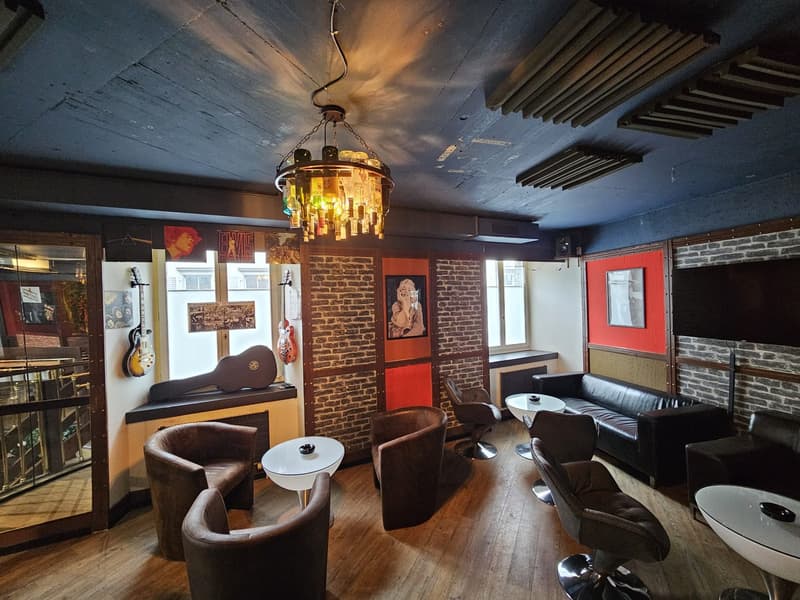 Interior of a bar with chairs, tables, a sofa, and musical instruments on the wall