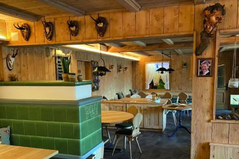 wooden walls, wooden tables, green cushioned seating, chairs, antlers and carved figures on the wall