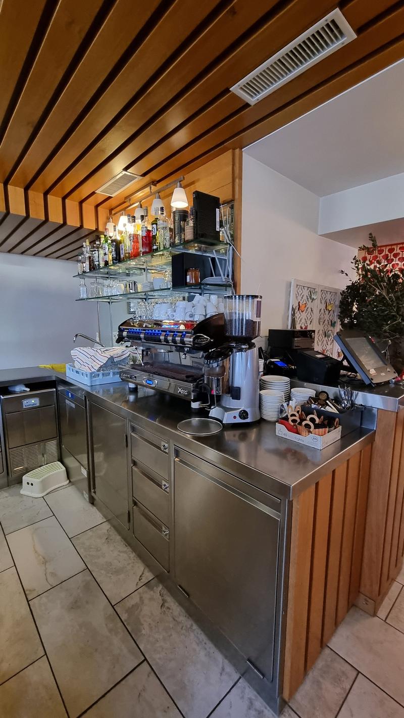 Counter with coffee machine, plates, bowls, utensils, and a plant