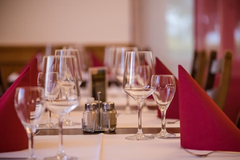 Table set for dining with wine glasses, red napkins, salt and pepper shakers, and forks