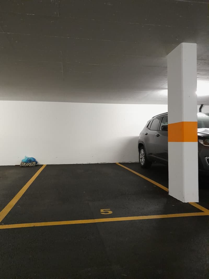 empty parking lot, yellow parking lines, white wall, gray SUV parked, number 5 marking, white pillar