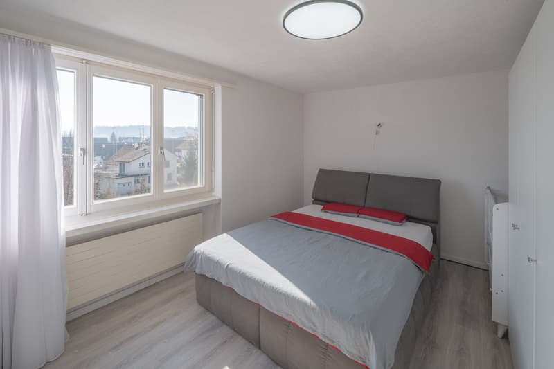 bedroom with bed, window, radiator, ceiling lamp, white curtains