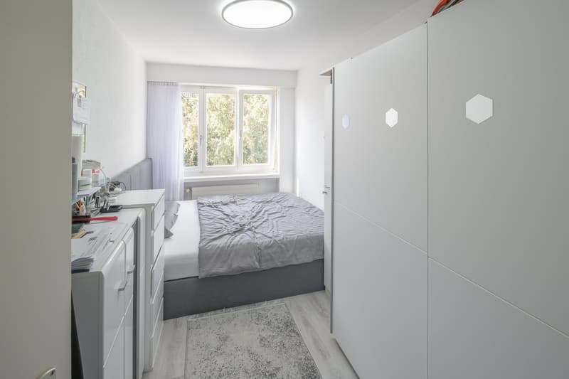Bedroom with bed, window, radiator, rug, wardrobe, desk, drawers, ceiling light