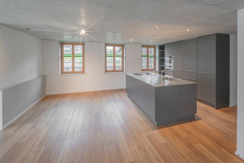open plan kitchen, wooden floor, white walls, large central island, three windows