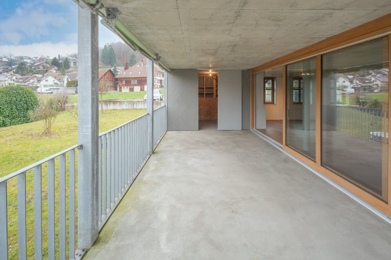 concrete balcony, metal railing, large glass doors, panoramic view of town and fields