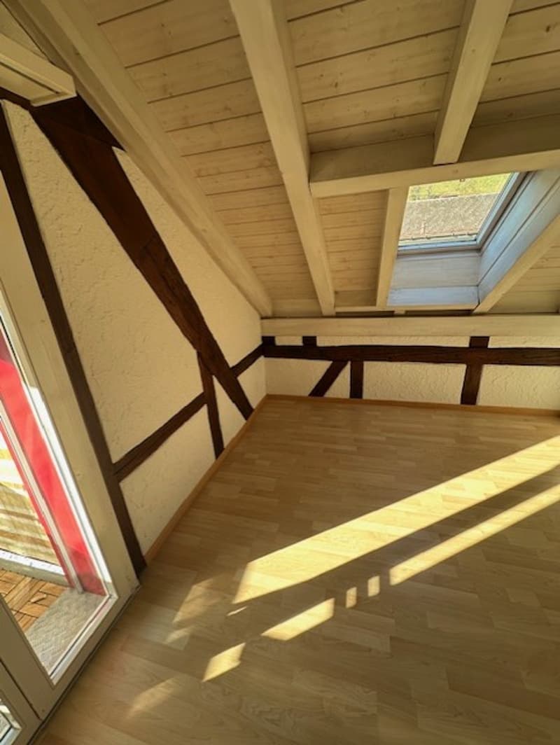 empty attic room, wooden floor, white ceiling, glass window, exposed rafters