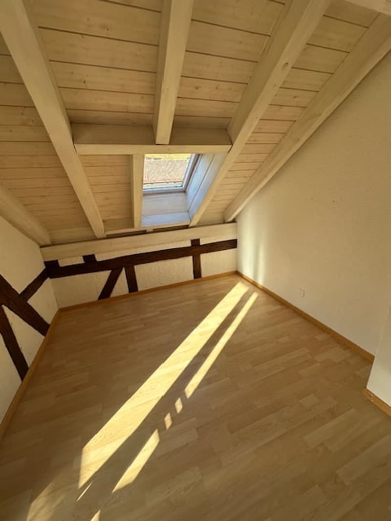 Empty attic room, wooden floor, wooden ceiling, skylight window, exposed beams