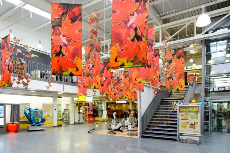 Indoor shopping mall with banners, gym equipment, stairs, and various stores