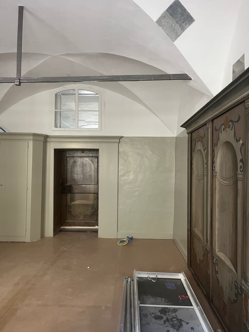 vaulted ceiling, arched doorway, wooden wardrobe, arched window, unfinished floor
