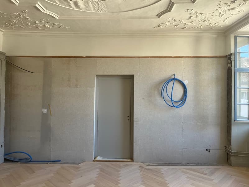 empty room, concrete walls, wooden floor, door, window, blue hoses