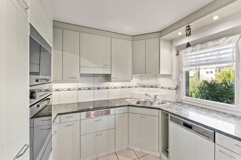 modern kitchen with built-in appliances, granite countertops, and white cabinetry