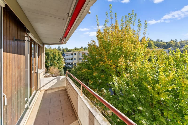 Balcony with wooden flooring, tiled wall, metal railing, glass door, access to an indoor area