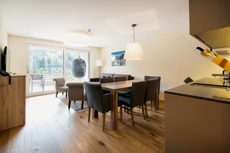 Offener Wohn- und Essbereich mit harmonischer Einrichtung, viel Tageslicht und direktem Zugang zum Balkon ein einladender Mittelpunkt für entspannte Ferienmomente.