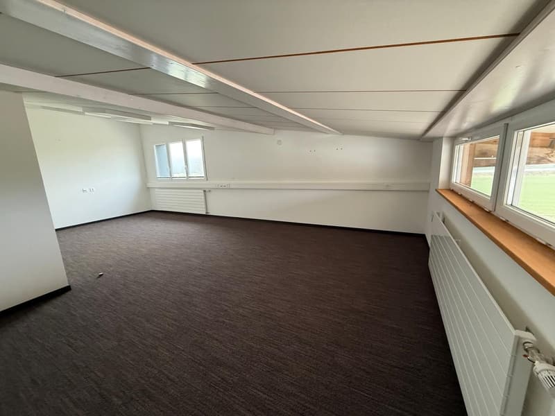 Empty room, white walls, windows, brown floor, wooden beams on ceiling, white radiators