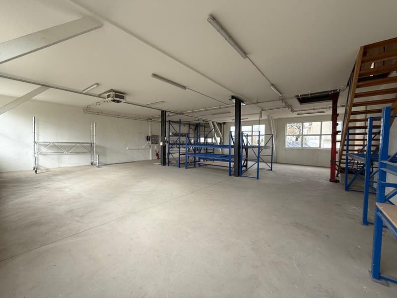 Wide and empty room, industrial, empty, white walls, bare floor, some shelves, windows