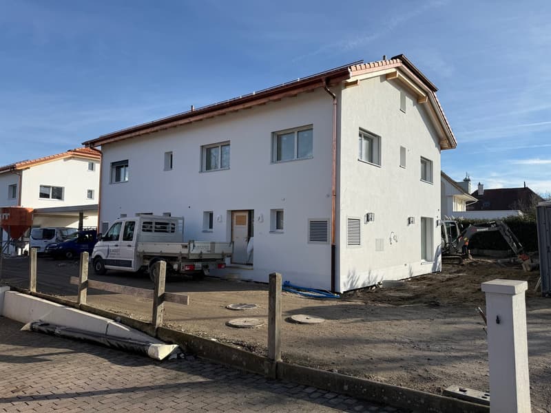 modern white house, two stories, brown roof, several windows, under construction, pickup truck, machinery vehicles, wooden fences