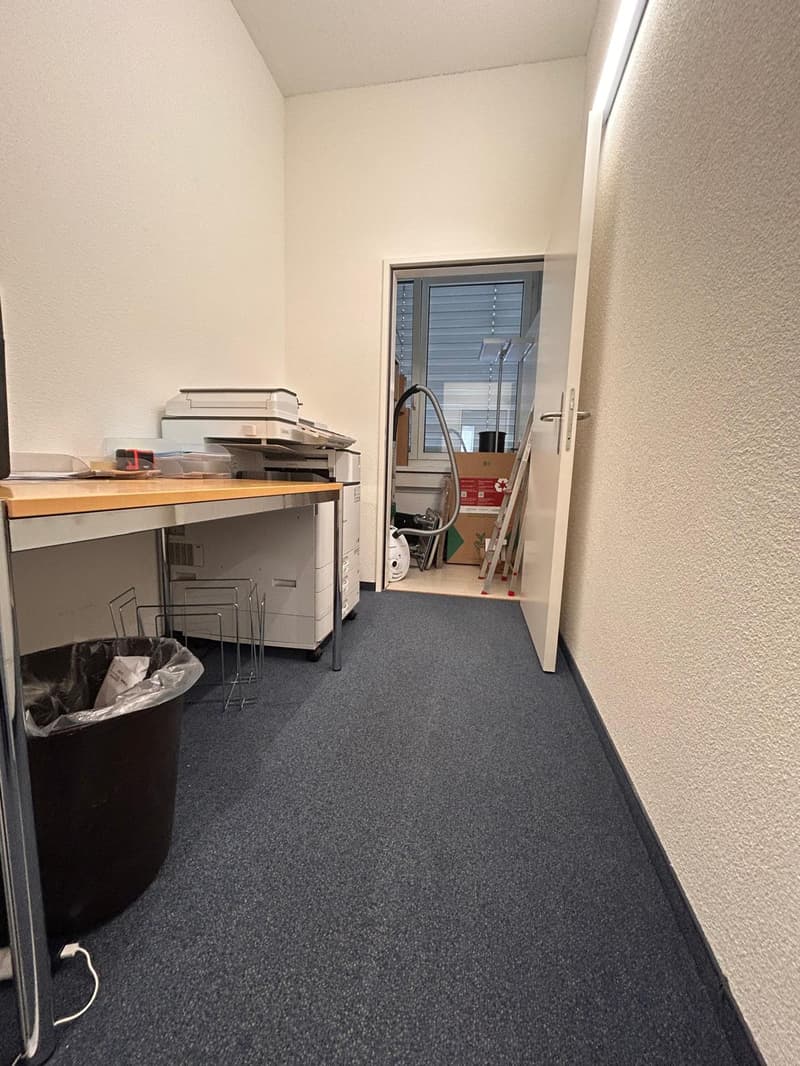 Empty room with wooden table, printer, and trash bin