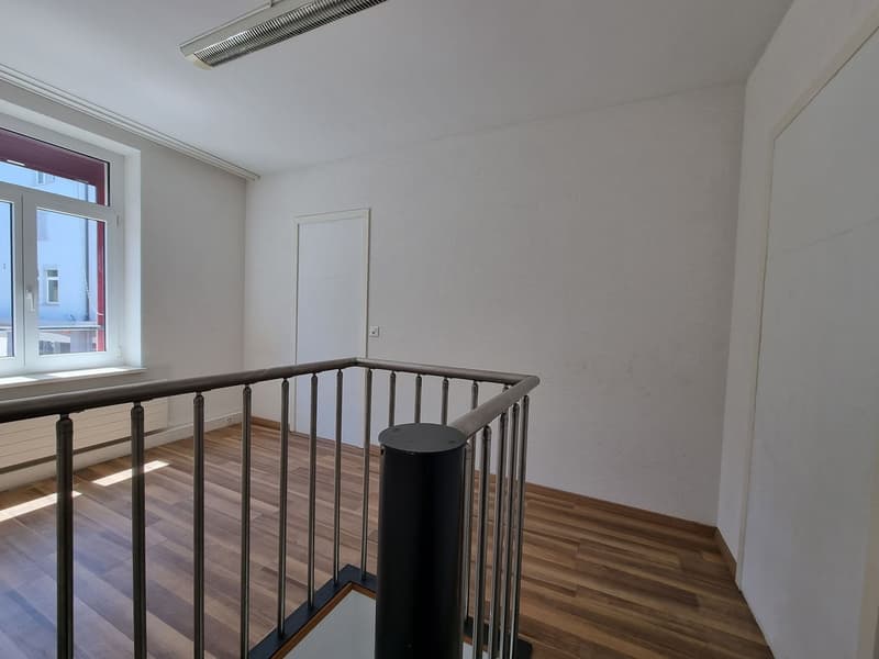 empty room, hardwood floor, steel handrail, white walls, closed door, window, pipe on ceiling