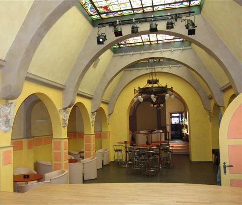 yellow walls, arched ceiling, chandelier, tables and chairs, spotlights