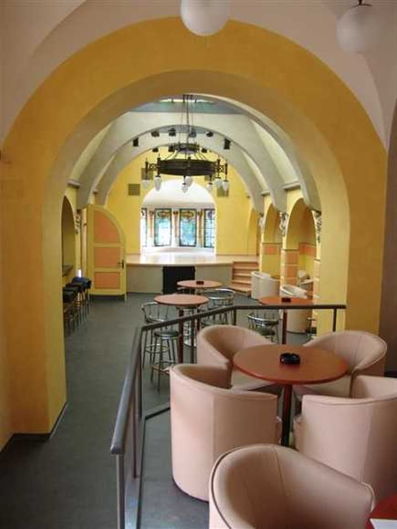 yellow walls, arched ceiling, round tables, chairs, chandelier, bar stools